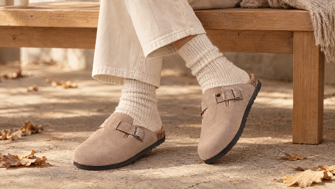 Chevilles croisées en chaussettes côtelées crème et mules en velours vegan taupe, assise sur un banc en bois